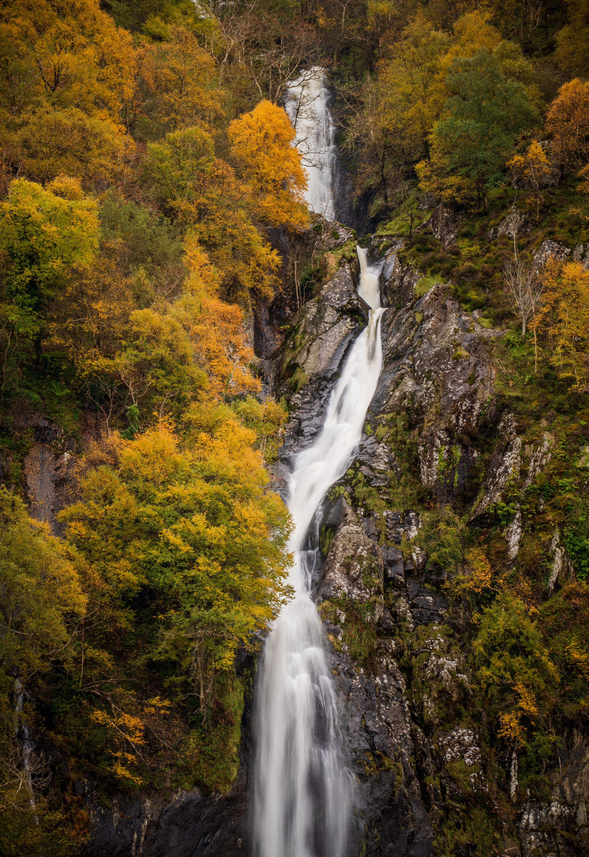 Aber Falls in North Wales, with autumnal trees on the cliffs surrounding them. Photography by Kieran Metcalfe - Prints Available.